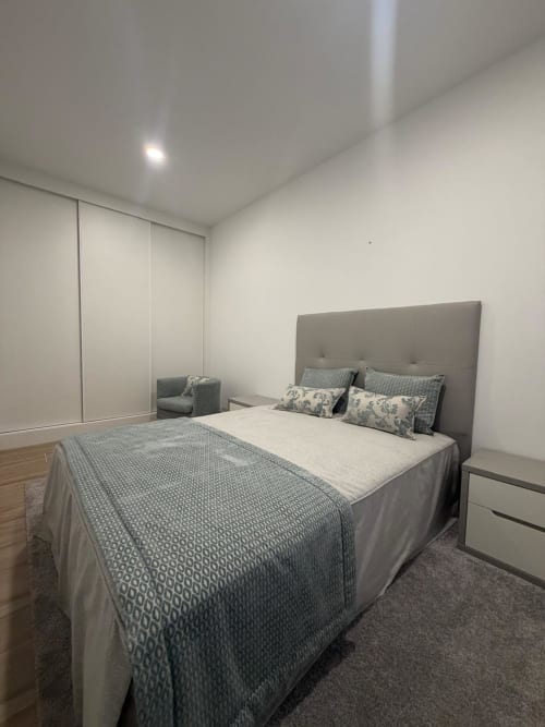 Quarto moderno na Galagana Charm House, Golegã com cama estofada cinza, guarda-roupa embutido e decoração minimalista