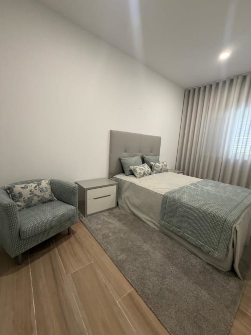 Quarto moderno na Galagana Charm House com cama, poltrona, criado-mudo e vista para o jardim em Golegã