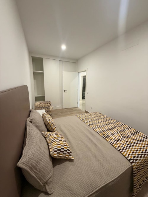 Quarto principal da Galagana Charm House em Golegã: cama com almofadas estampadas, guarda-roupa e porta do banheiro suíte