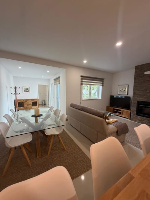 Sala de estar e jantar em conceito aberto na Galagana Charm House com mesa de vidro, assentos confortáveis, TV e lareira