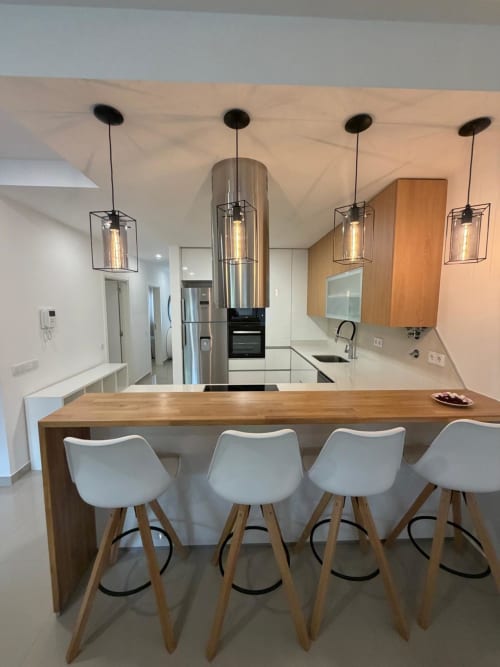 Cozinha moderna na Galagana Charm House com ilha de madeira, banquetas brancas, luminárias pendentes e eletrodomésticos de aço inoxidável
