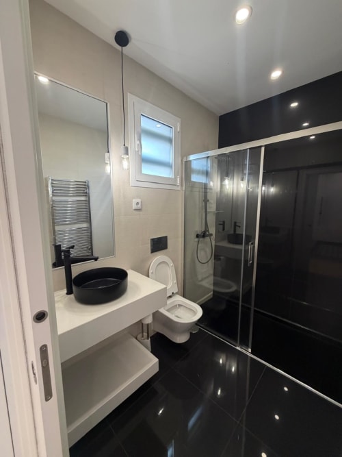 Banheiro moderno na Casa Charm Galagana, Golegã - pia preta, vaso sanitário branco, chuveiro de vidro, teto branco com spots embutidos