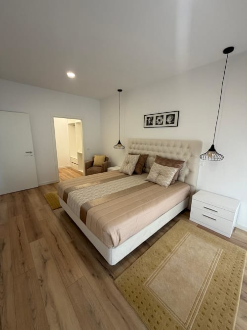 Quarto moderno na Galagana Charm House em Golegã com cama queen, criado branco, luminárias pendentes e piso de madeira