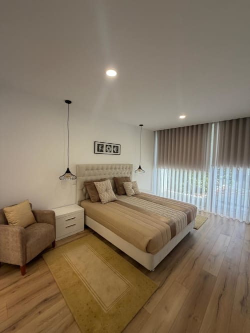 Quarto moderno na Galagana Charm House com cama queen, luminárias pendentes, poltrona e vista para o jardim em Golegã