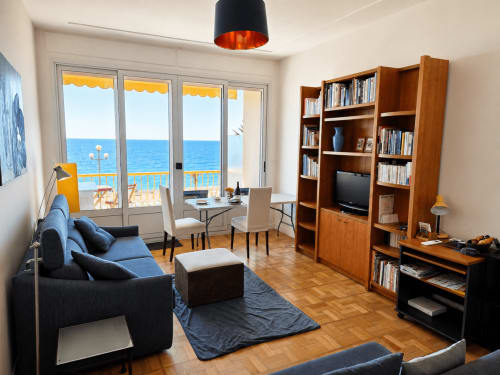 Sunny sea-view apartment at Enjoy Nice with blue seating, wooden shelving, and Mediterranean balcony views