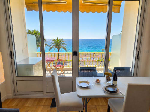 Sundeck apartment in Nice with dining table, sea view, palm trees, and Mediterranean balcony with yellow awning