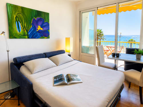 Bright bedroom with sea view at Enjoy Nice hotel, featuring blue bed, artwork, and Mediterranean balcony access in Nice,