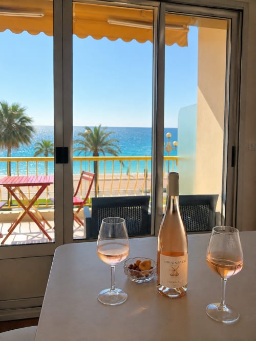 Rosé wine and glasses on table overlooking Mediterranean Sea in Nice apartment with beach view