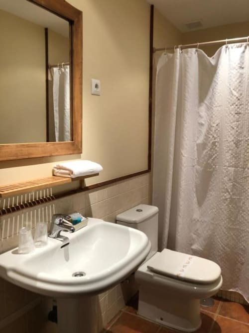 Baño de Casa Rural El Infante con lavabo, inodoro, ducha, espejo y toallas blancas en Oropesa