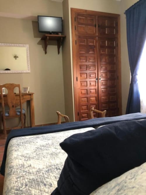 Habitación doble en Casa Rural El Infante en Oropesa con armario de madera, cama, televisor y decoración tradicional