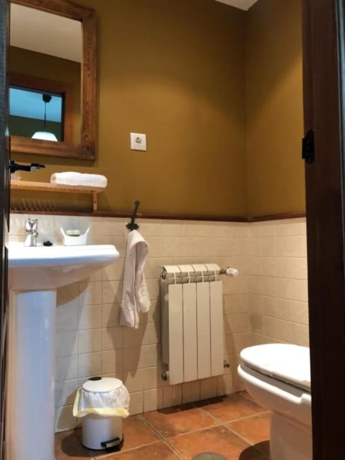 Baño moderno en Casa Rural El Infante, Oropesa con lavabo de pedestal, inodoro, toallero calefactor y paredes ocre dorado