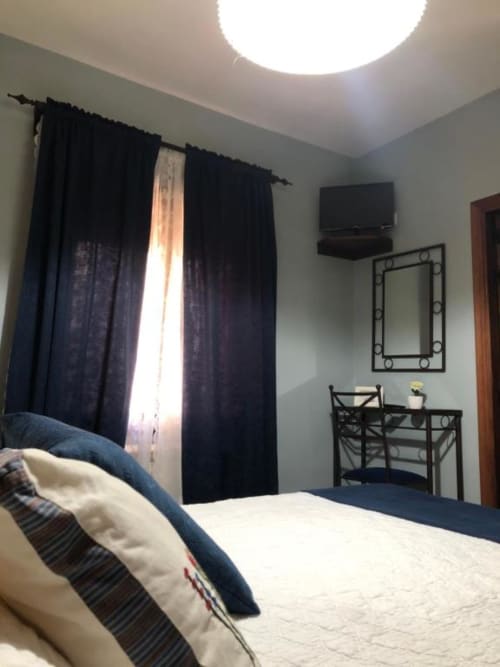 Luminoso dormitorio doble en Casa Rural El Infante de Oropesa con TV, escritorio, cortinas negras y comodidades modernas