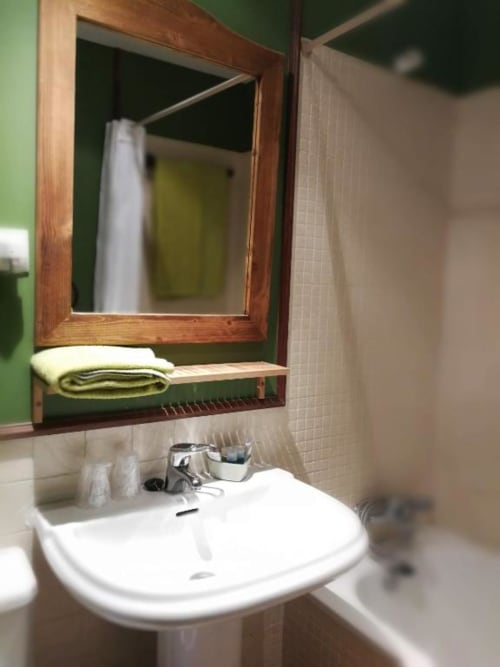 Baño de Casa Rural El Infante con lavamanos de pedestal blanco, espejo con marco de madera y paredes verdes