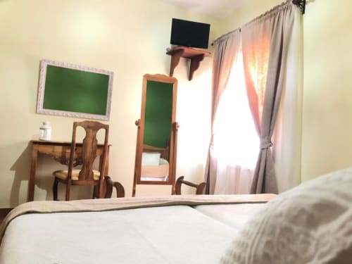 Luminoso dormitorio doble en Casa Rural El Infante de Oropesa con muebles de madera, televisor de pantalla plana, espejo y luz natural