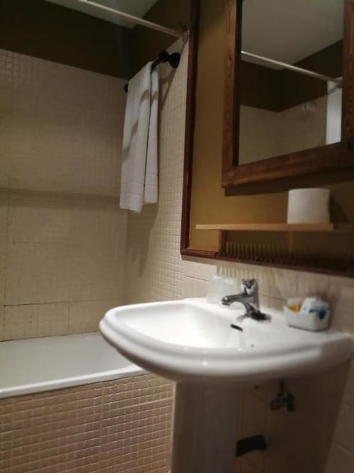 Baño de Casa Rural El Infante en Oropesa con lavabo pedestal, espejo, bañera y toallas blancas