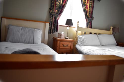 Twin bedroom at Knockaderry House B&B in Ennis with two single beds, wooden furniture, and colorful curtains