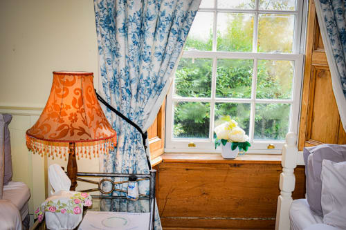 Deluxe twin room at Knockaderry House B&B in Ennis with garden views, orange lamp, blue floral curtains, and wooden window