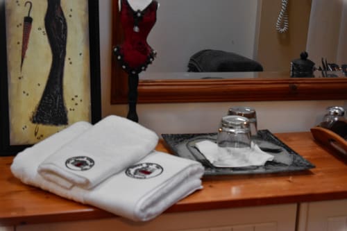 White towels with emblem and glass dispensers on wooden desk at Knockaderry House B&B in Ennis