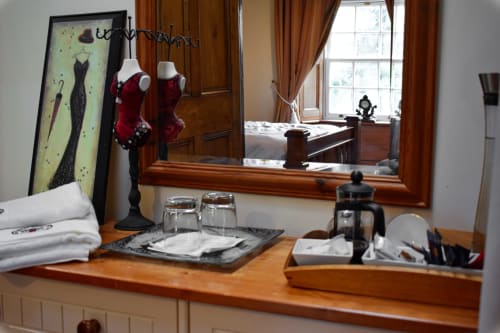 Knockaderry House bathroom vanity with wooden counter, mirror, toiletries, towels, and red dress form display, Ennis B&B