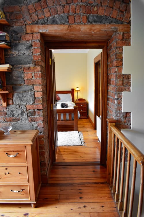 Knockaderry House double room hallway with exposed brick archway, wooden floors, and view into bedroom with bed and lamp