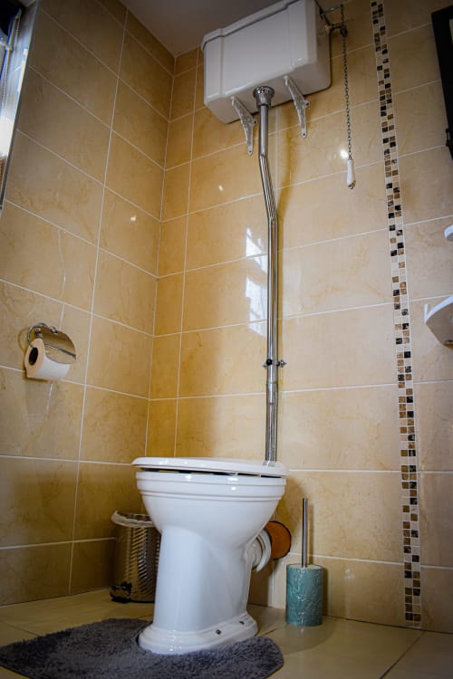 Private bathroom in Twin Room at Knockaderry House, Ennis, featuring white toilet, beige tiled walls, and shower facilities