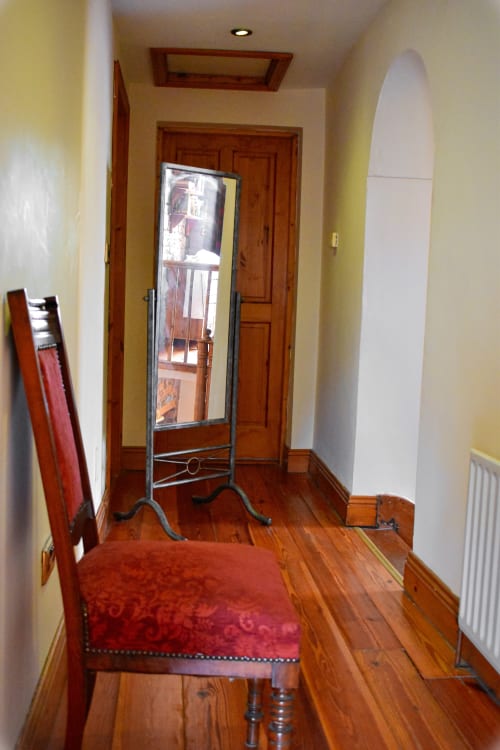Hallway at Knockaderry House B&B in Ennis with wooden flooring, red chair, and standing mirror