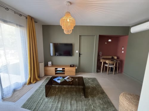 Chambre moderne à la Résidence Les 3 Volcans avec murs verts, téléviseur, mobilier en bois et luminaires suspendus à Clermont-Ferrand