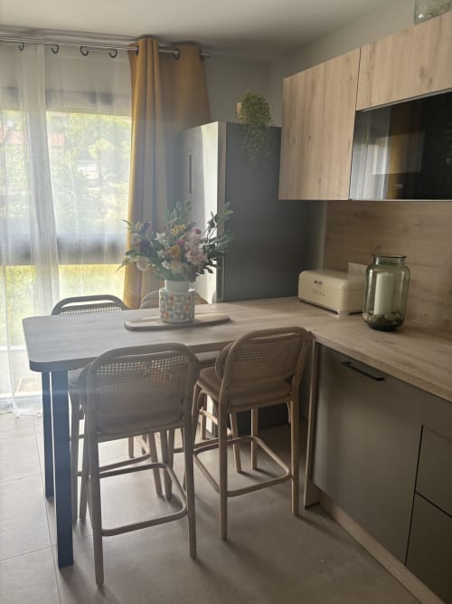 Cuisine moderne avec coin bar à la Résidence Les 3 Volcans, Clermont-Ferrand. Vue sur le jardin par les fenêtres.