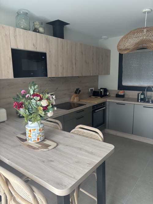 Cuisine moderne à la Résidence Les 3 Volcans Clermont-Ferrand avec meubles en bois, îlot central et fleurs fraîches