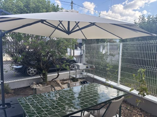 Terrasse de jardin extérieure de la Résidence Les 3 Volcans avec parasol, table à manger et clôture blanche à Clermont-Ferrand