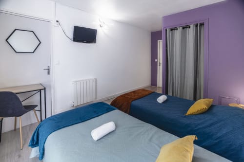 Chambre twin moderne à l'Hôtel De La Bonnheur à Bracieux avec lits bleus, murs violets, TV et bureau