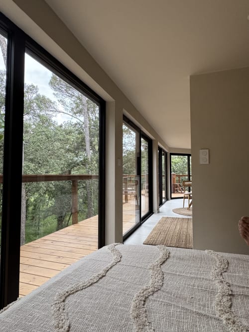 Chambre avec vue sur la forêt par de grandes fenêtres et terrasse en bois au Domaine d'Olga, Aniane