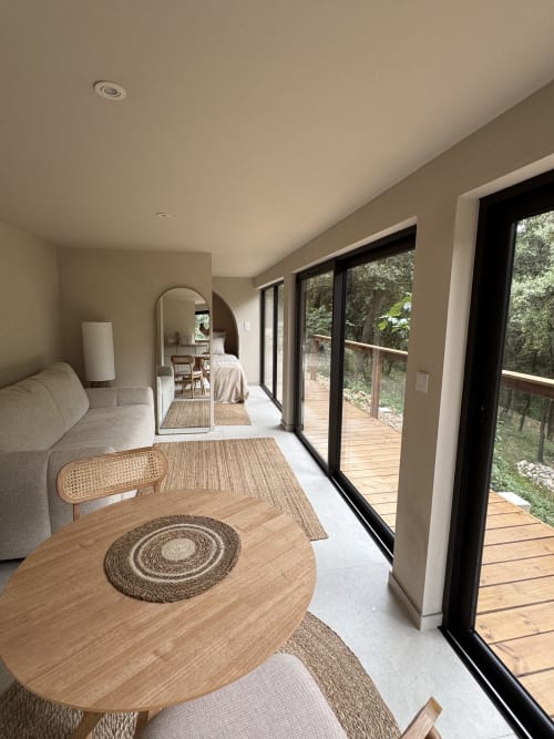 Suite moderne au Domaine d'Olga avec table de salle à manger en bois, vue sur jardin par portes à cadre noir et design contemporain
