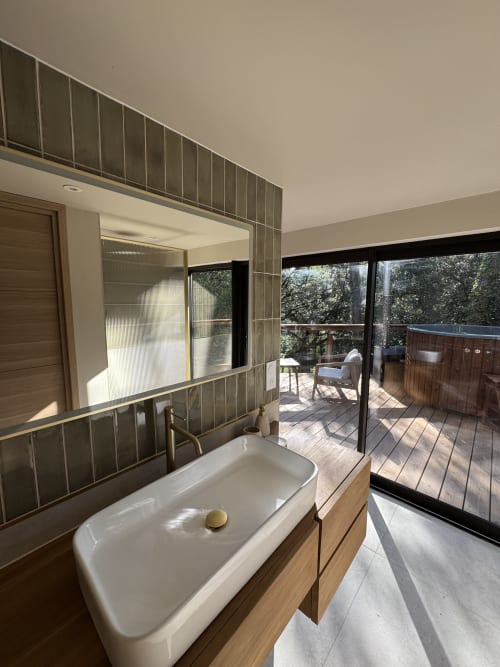 Salle de bains moderne au Domaine d'Olga avec vanité en bois, grand miroir et vue jardin par portes coulissantes