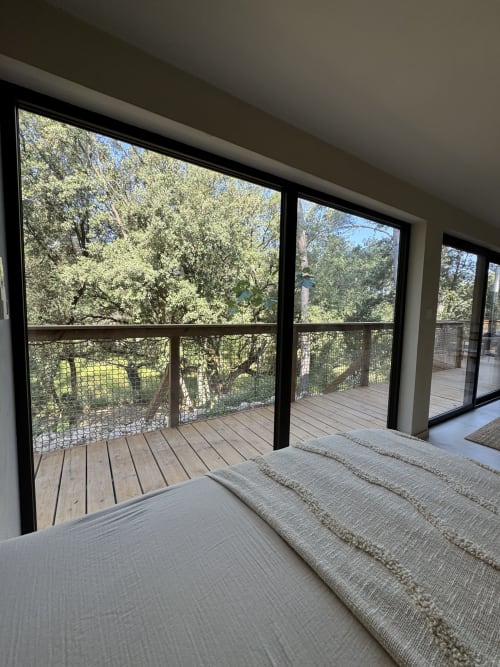 Chambre moderne avec vue sur le jardin depuis les larges portes coulissantes ouvrant sur la terrasse en bois, Domaine d'Olga à Aniane