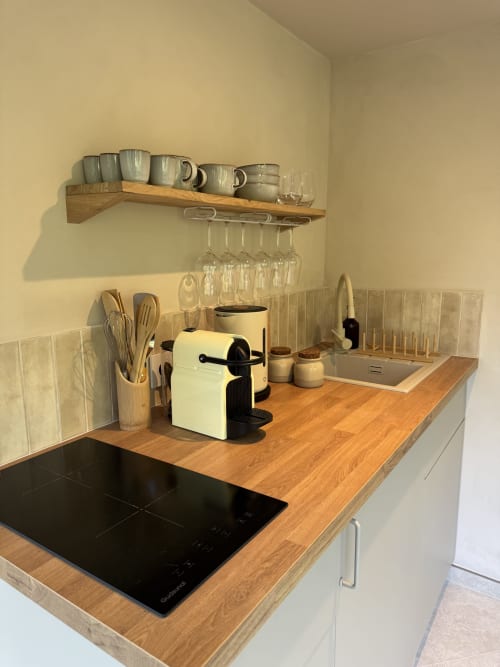 Kitchenette moderne à la Domaine d'Olga à Aniane : comptoirs en bois, plaque à induction et rangements ouverts