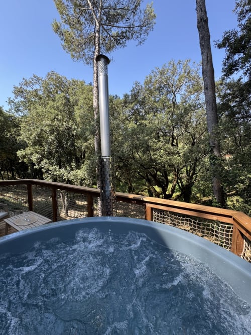 Jacuzzi bouillonnant sur une terrasse en bois entourée d'arbres au Domaine d'Olga, Aniane France
