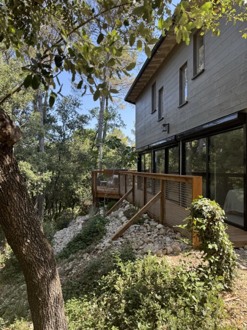 Extérieur moderne du lodge Domaine d'Olga à Aniane avec terrasse bois, balustrades métalliques, grandes baies et jardin paysagé