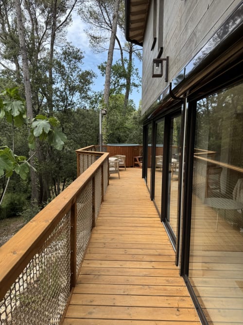 Terrasse en bois moderne avec portes à cadre noir au Lodge du Grand Chêne, Domaine d'Olga, Aniane