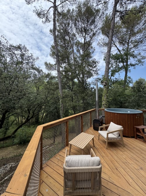 Terrasse en bois avec salon de détente surplombant un jardin forestier à Domaine d'Olga, Aniane, avec bain à remous et grands pins