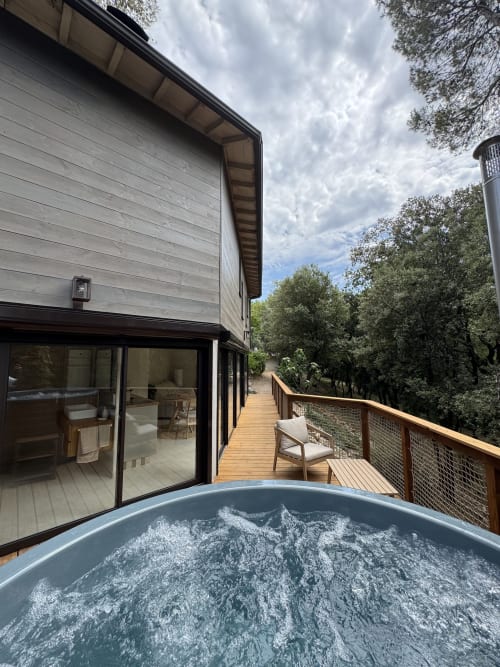 Jacuzzi sur terrasse en bois avec vue sur les jardins du domaine d'Olga à Aniane, France
