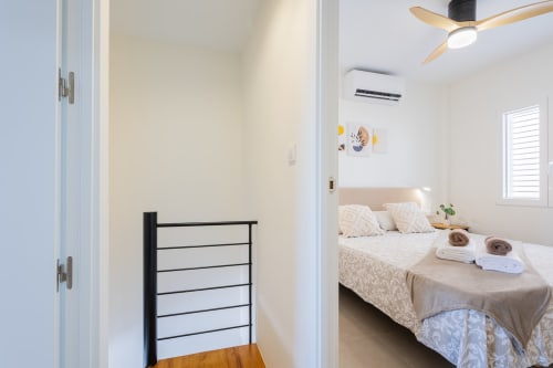 Pasillo hacia dormitorio luminoso en dúplex Haus Holiday Homes en San Javier, España con muebles modernos y ventilador de techo.