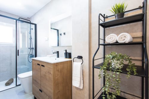 Baño moderno con tocador de madera, estantería negra con toallas y plantas en Haus Holiday Homes, San Javier