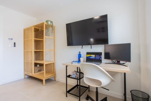 Espacio de trabajo moderno en casa de Haus Holiday Homes con dual monitors, estantería de madera y escritorio en San Javier
