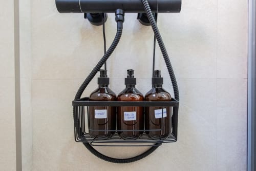 Tres botellas ámbar etiquetadas con dispensadores de spray montados en la pared de Haus Holiday Homes, San Javier