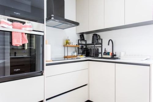 Cocina blanca moderna con encimeras negras, electrodomésticos Whirlpool y comodidades estilo casa de playa en Haus Holiday Homes