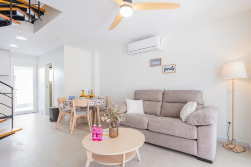 Sala de estar de dúplex moderno con sofá gris, comedor y vistas al mar cerca de San Javier