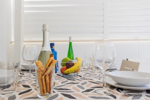 Elegante mesa de comedor en Haus Holiday Homes San Javier con vino, frutas frescas y pan sobre mantel estampado