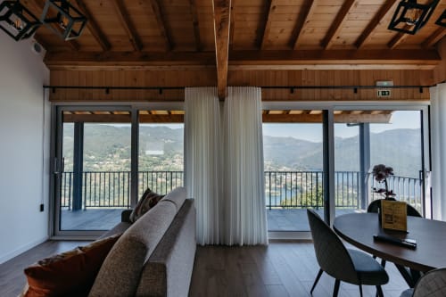 Interior moderno da villa em Villas Eden com vista panorâmica de montanhas, sofá cinzento e portas de vidro que se abrem para uma varanda deslumbrante