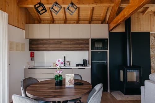 Cozinha-sala de jantar moderna da Villas Eden com teto de madeira, mesa redonda, flores rosa e eletrodomésticos pretos